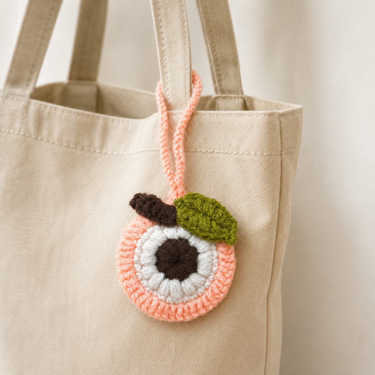 Crochet peach mini pouch hanging from a canvas tote bag