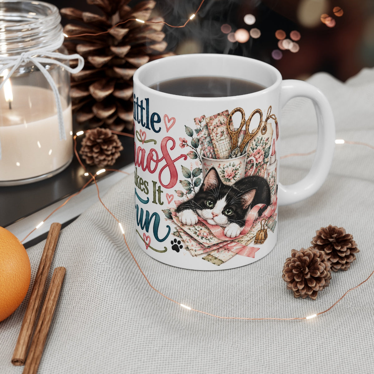 A Little Chaos Makes It Fun tuxedo cat ceramic mug styled with candle and pinecones