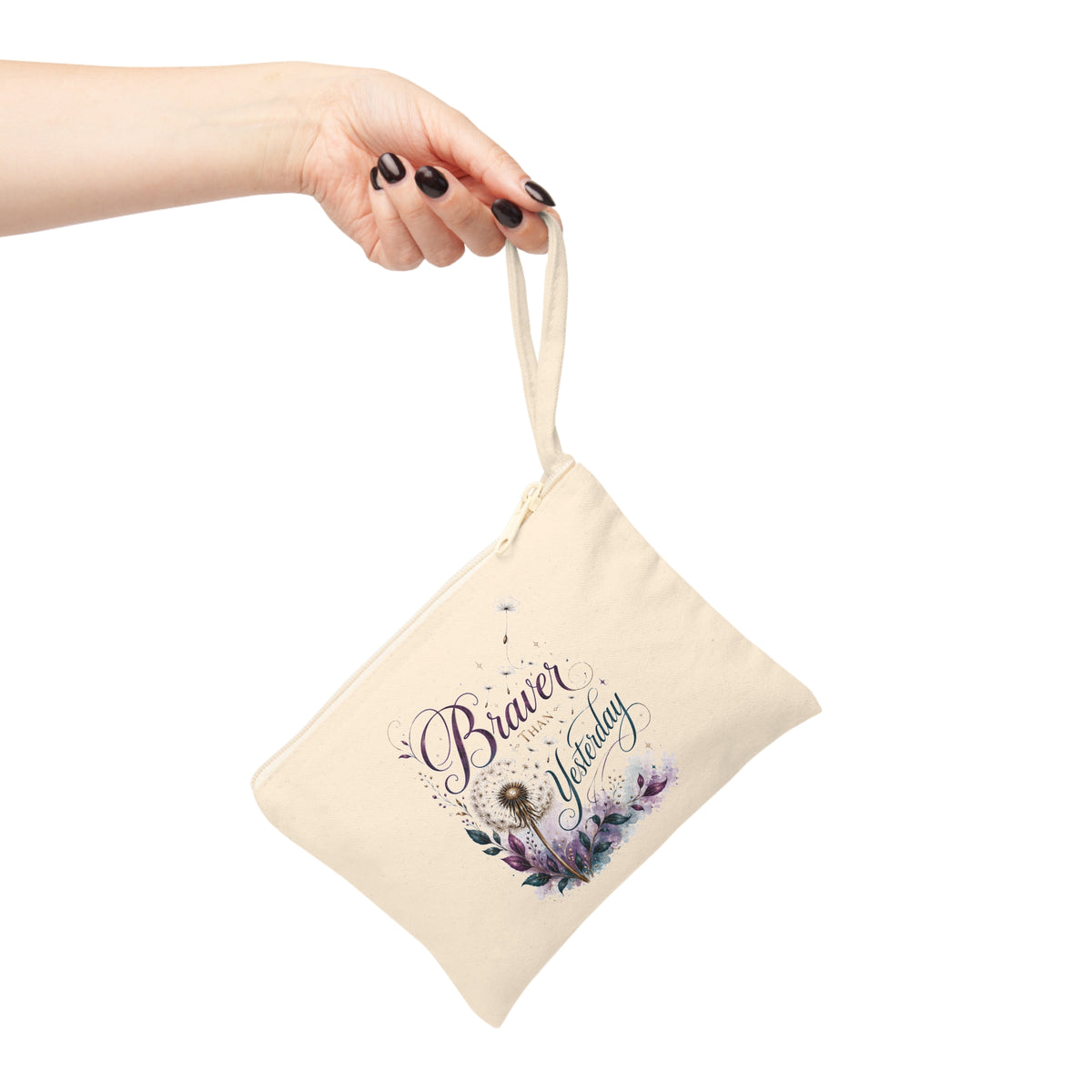 Braver Than Yesterday canvas wristlet pouch held by strap, featuring dandelion and purple botanical design