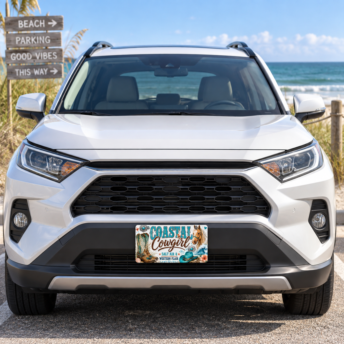 Coastal Cowgirl decorative license plate mounted on a white vehicle near the beach