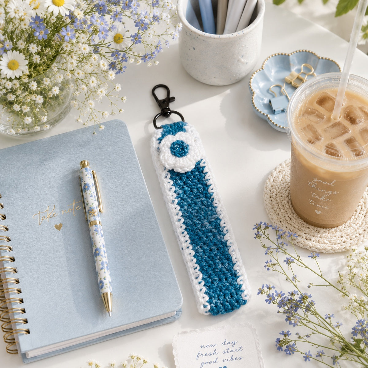 Bluebell Bloom crochet floral wristlet with blue notebook and iced coffee