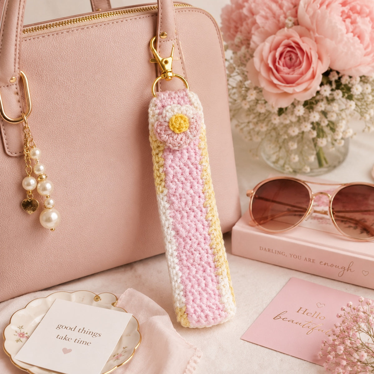 Blush Daisy crochet floral wristlet clipped to pink handbag