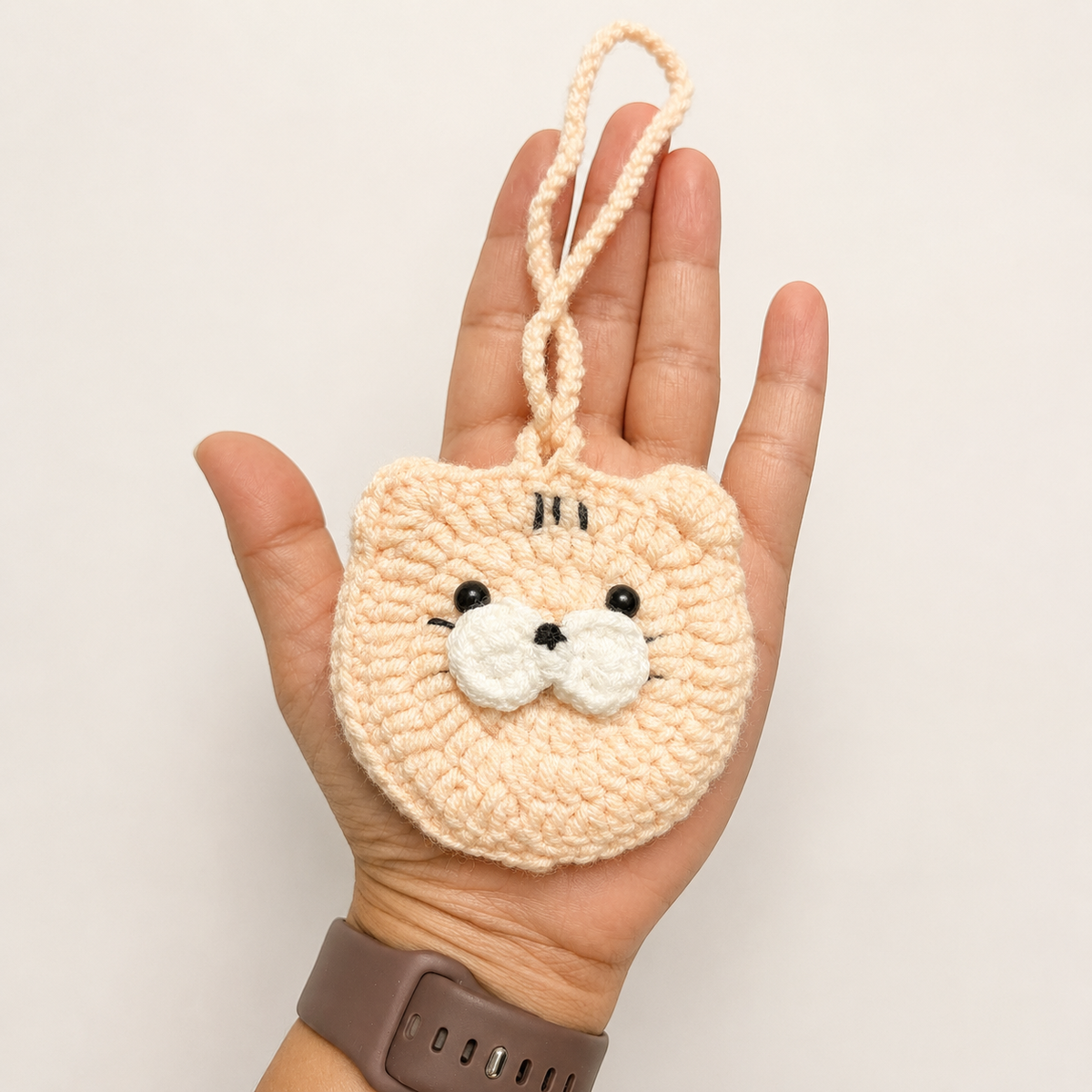 Handmade peach crochet cat mini pouch shown in hand for size