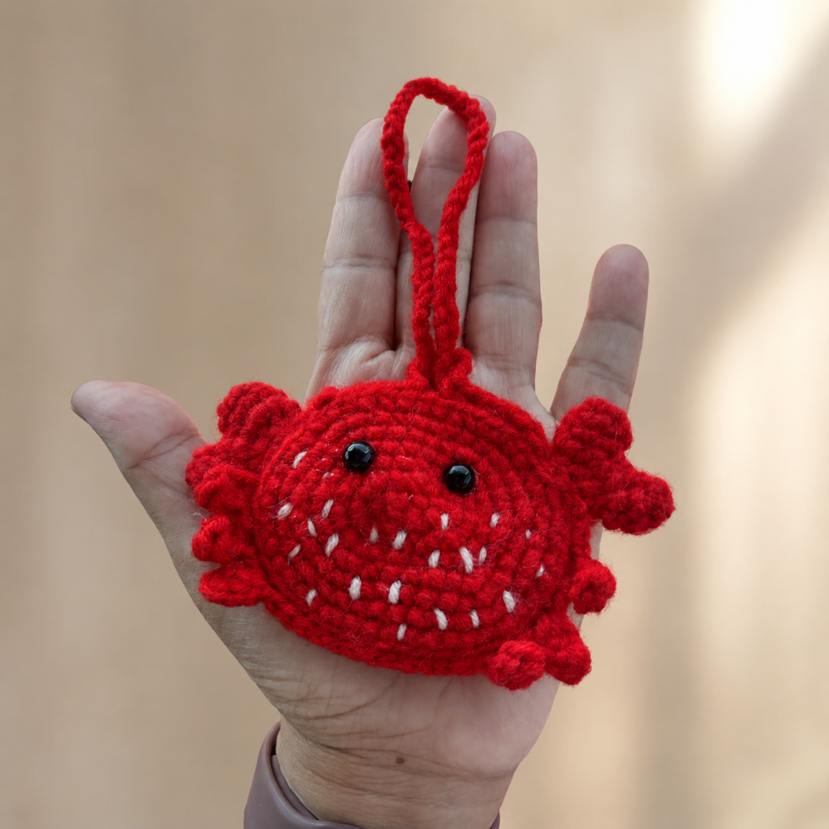 Handmade red crochet crab mini pouch shown in hand for size
