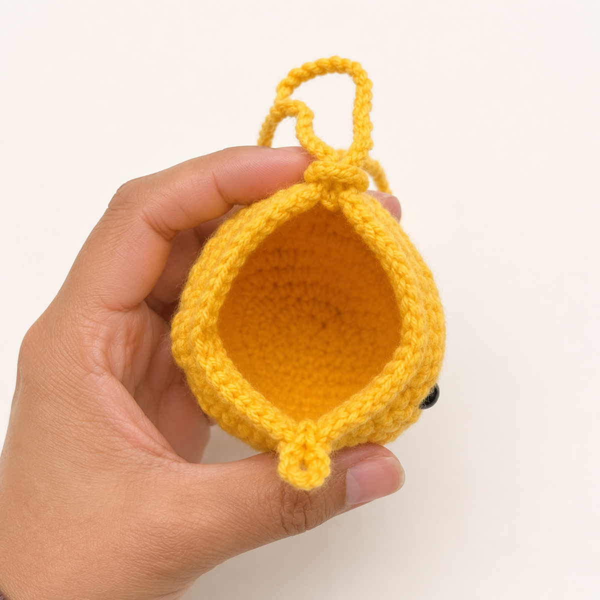 Open handmade yellow crochet duck mini pouch showing empty unlined interior