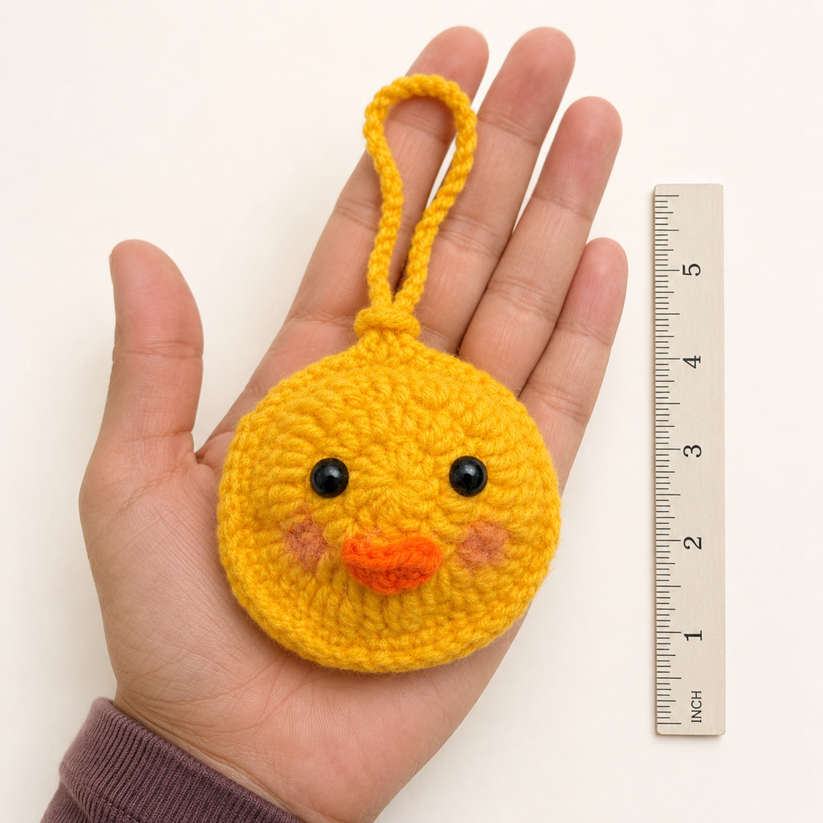 Handmade yellow crochet duck mini pouch shown in hand for size