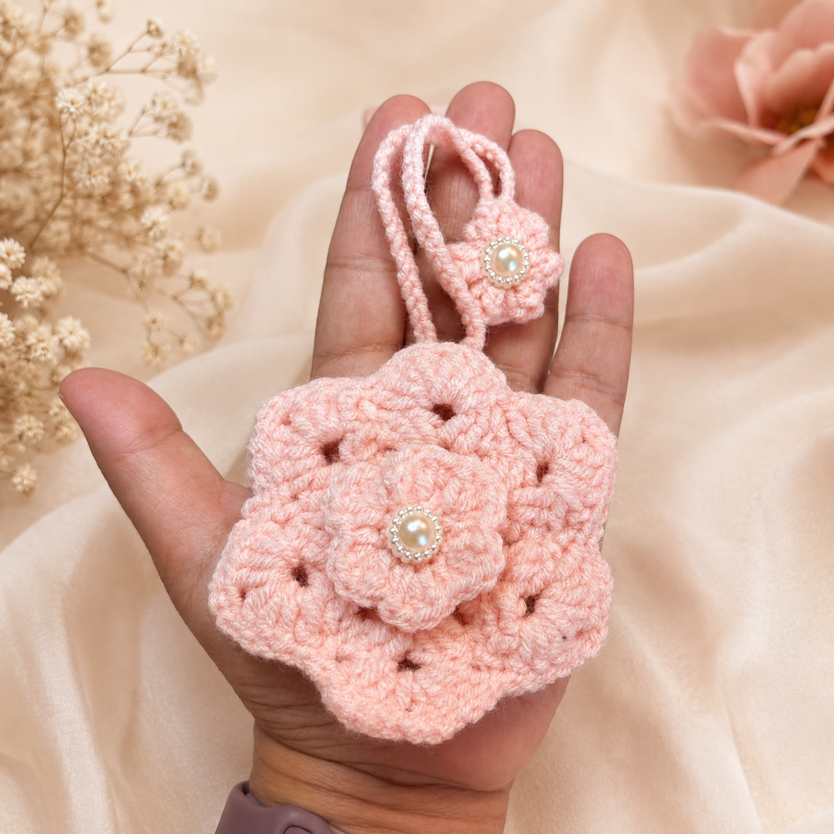 Handmade pink crochet flower key holder shown in hand for size
