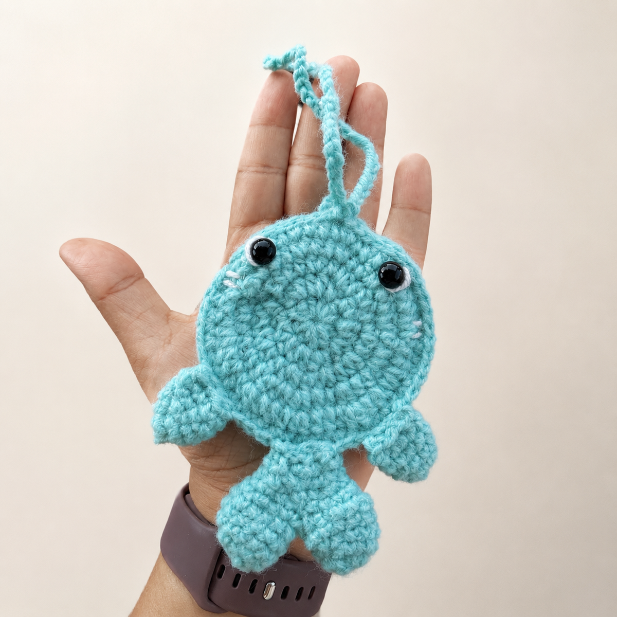 Handmade crochet whale pouch shown in hand for size