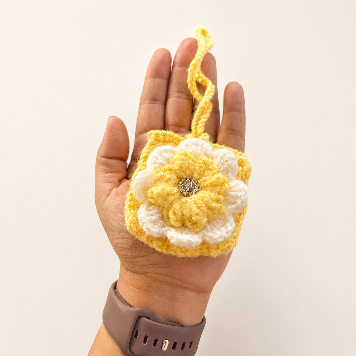 Handmade yellow crochet flower mini pouch shown in hand for size