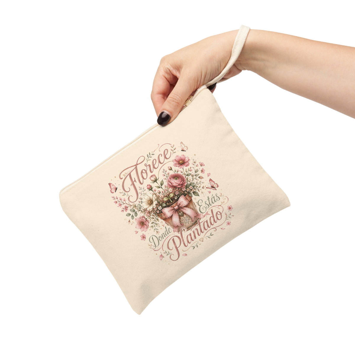 Hand holding a Florece Donde Estás Plantado canvas pouch with blush flowers, butterflies and a decorative bow.