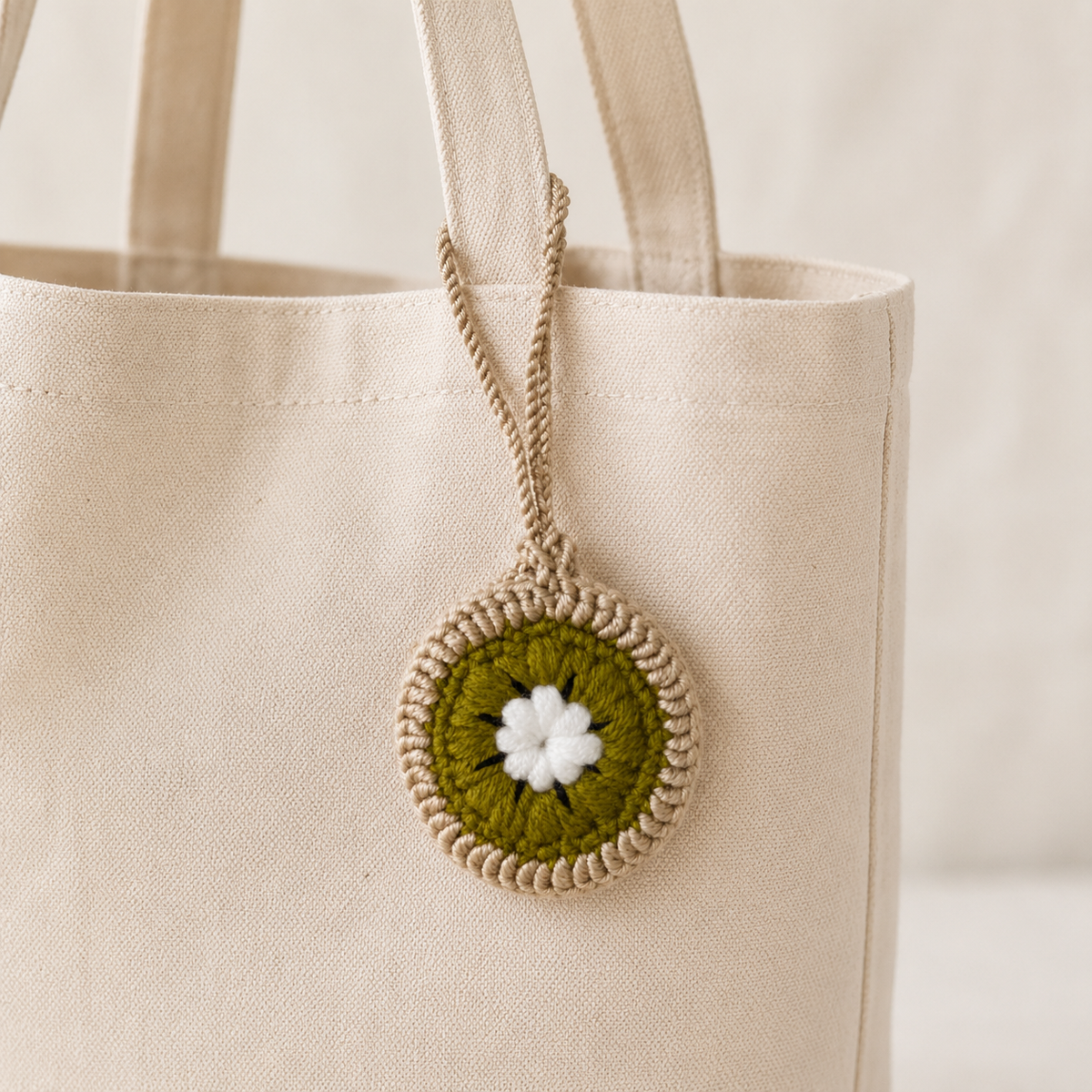 Crochet kiwi mini pouch hanging from a canvas tote bag
