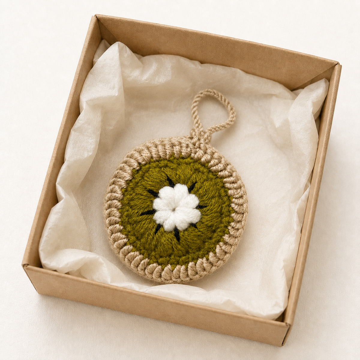 Handmade crochet kiwi mini pouch in a kraft gift box