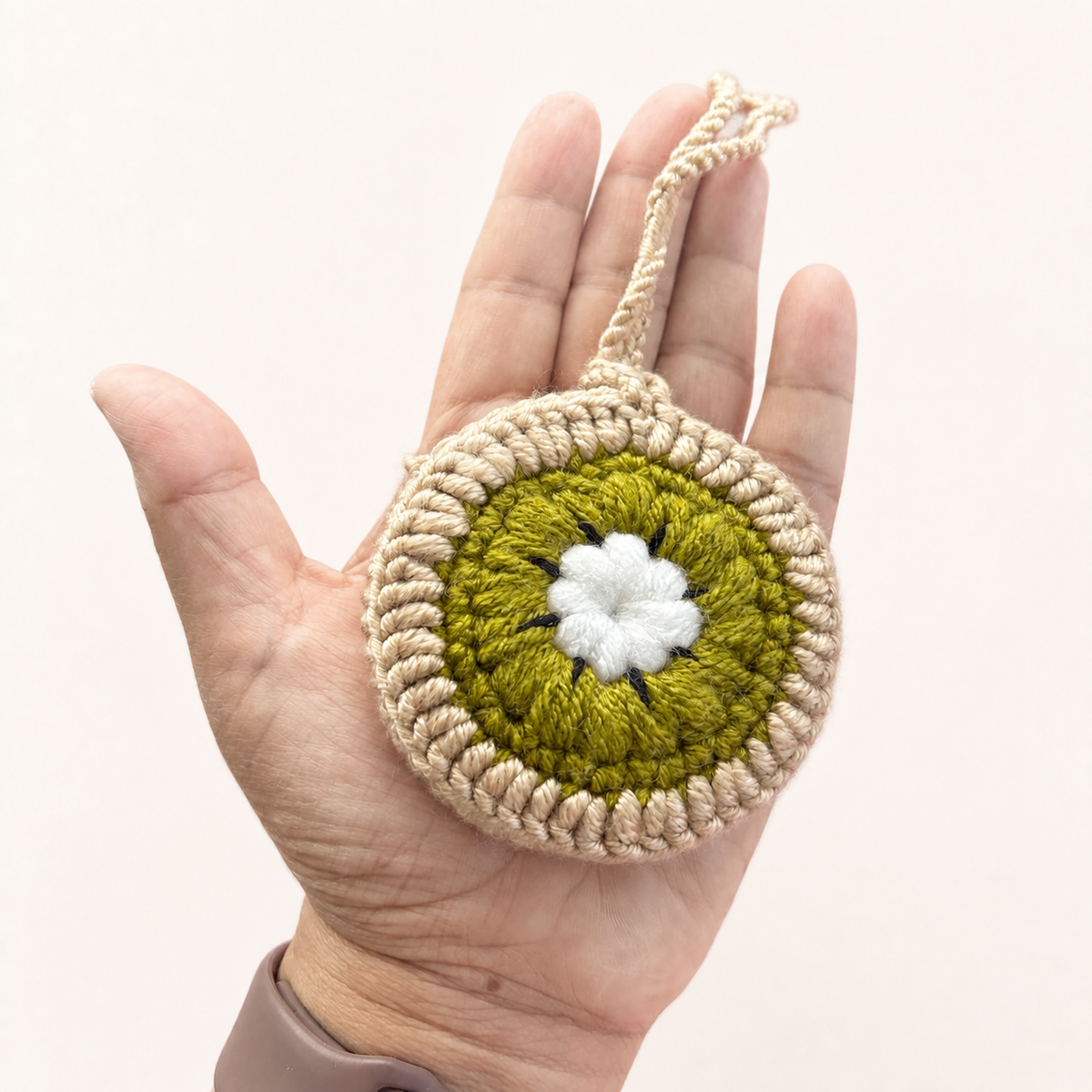 Handmade crochet kiwi mini pouch shown in hand for size