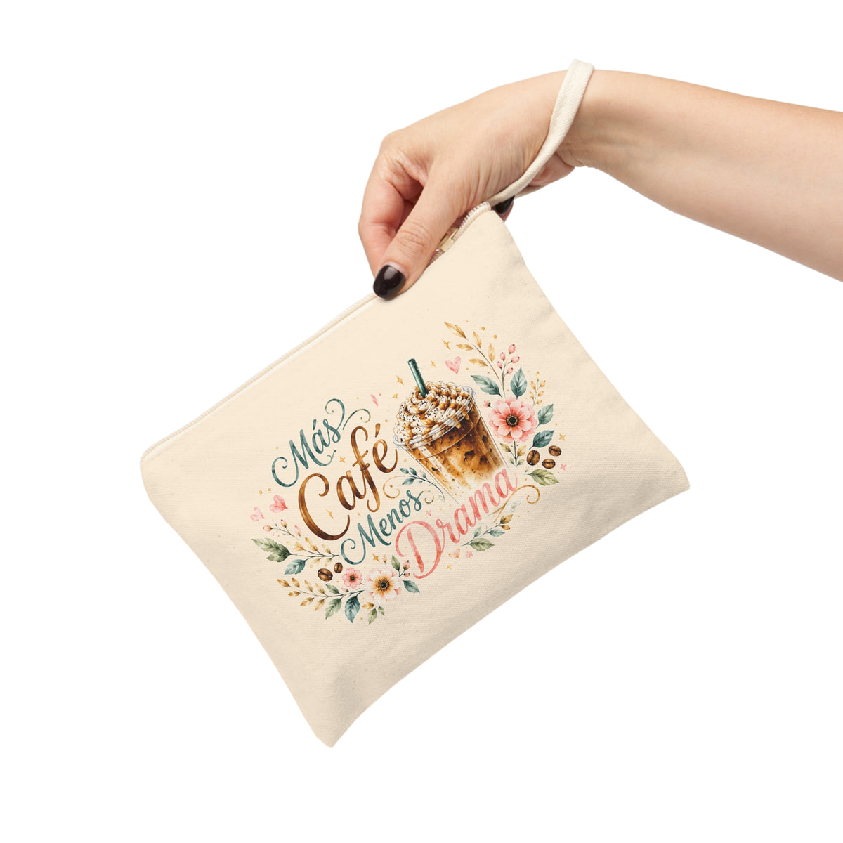 Hand holding a Más Café Menos Drama canvas pouch with iced coffee, coral flowers, green leaves and coffee beans.