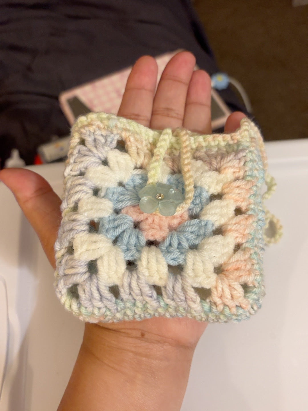 Pastel crochet pouch shown in hand for scale