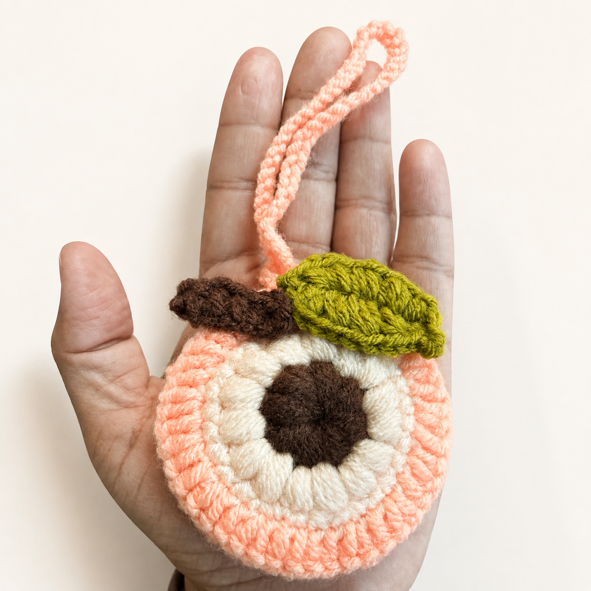 Handmade crochet peach mini pouch shown in hand for size