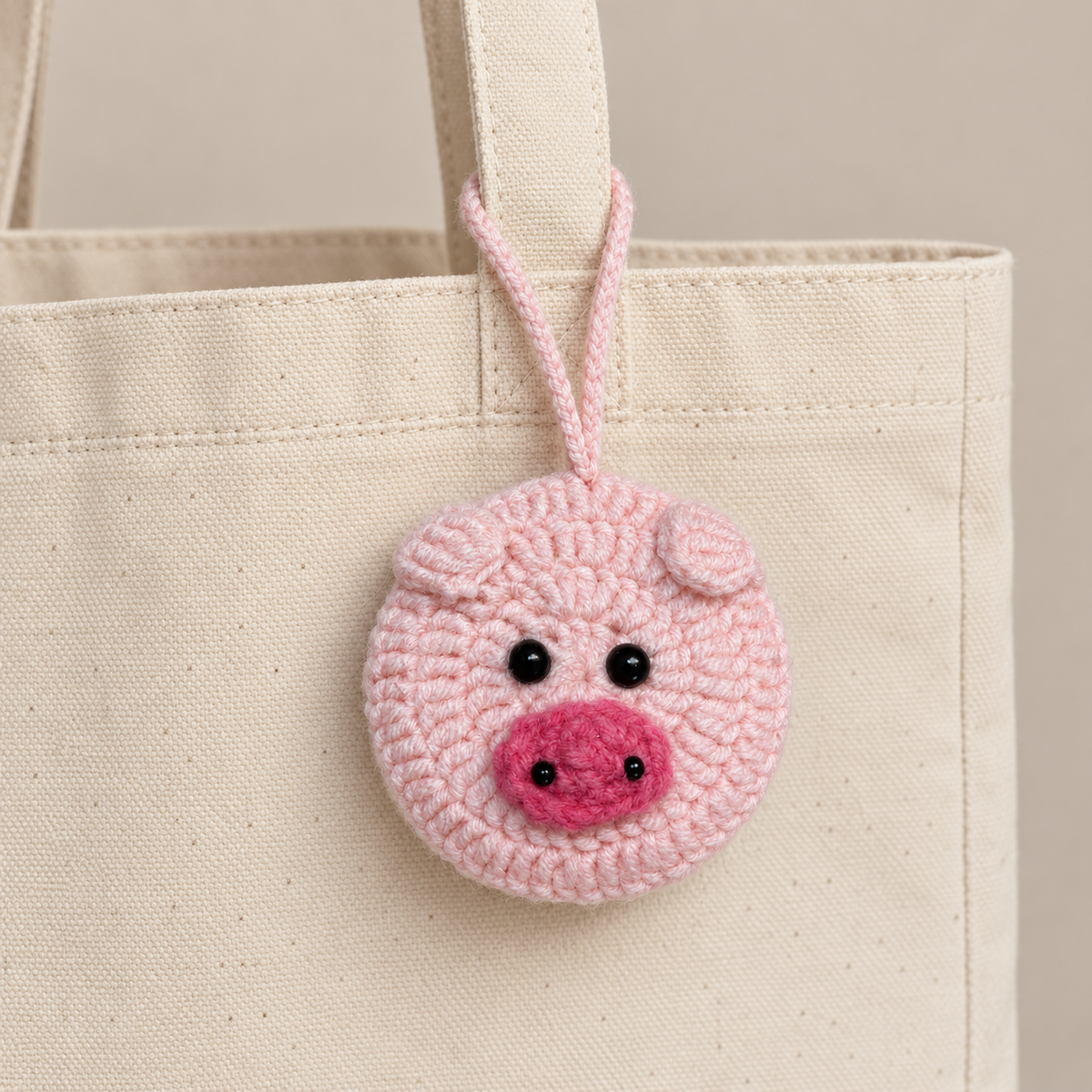 Pink pig crochet pocket mirror charm hanging from a canvas tote