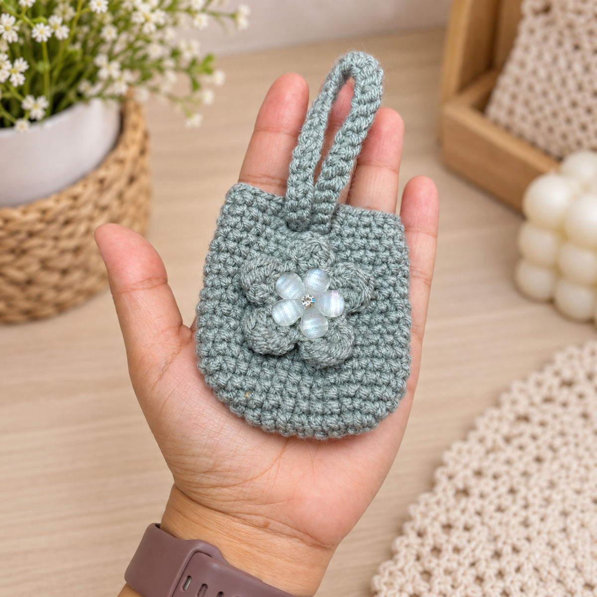 Handmade sage crochet mini wristlet pouch shown in hand for size reference
