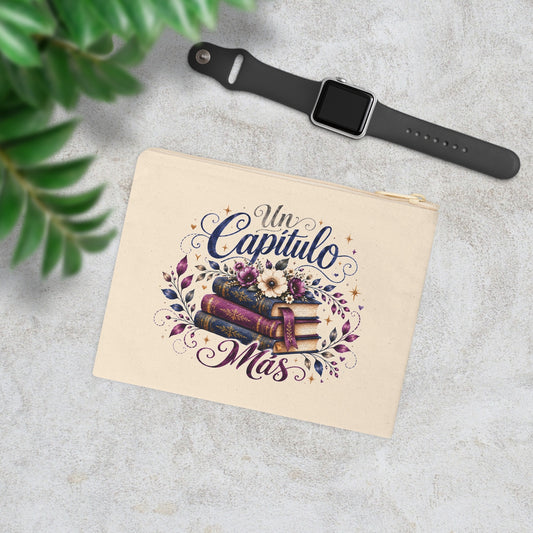 Un Capítulo Más canvas wristlet pouch with navy and purple books and floral design in a styled lifestyle scene.