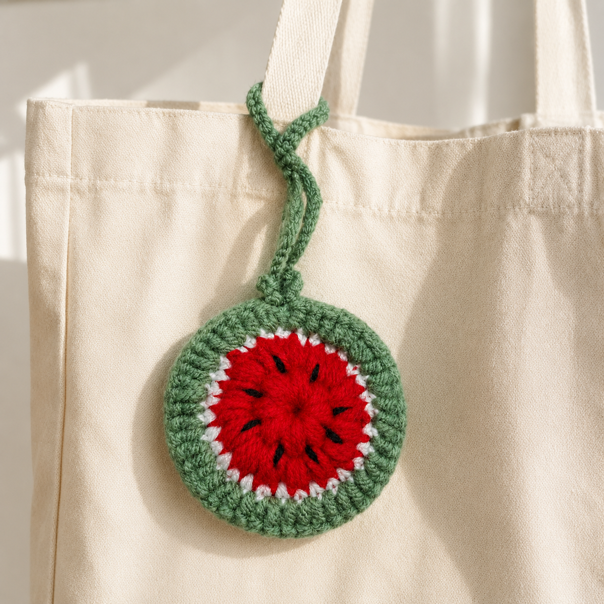 Crochet watermelon mini pouch hanging from a cream tote bag
