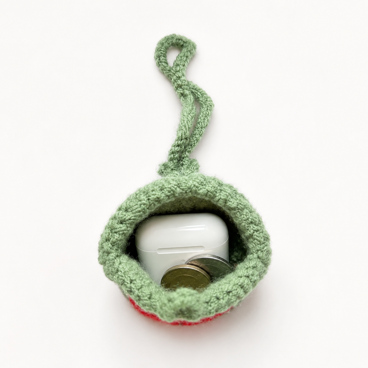 Open crochet watermelon mini pouch holding coins and wireless earbuds